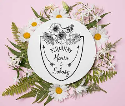 Pieczątka do ozdabiania zaproszeń ślubnych i pozostałej papeterii ślubnej z imionami pary młodej, datą ślubu i kwiatami. Całość wkomponowana została w ozdobną tarczę