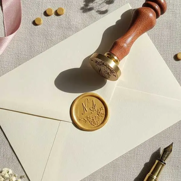 Stempel do laku okrągły 25 mm, mosiężny z drewnianym trzonkiem, złote odbicie z napisem, kolekcja stempli pieczęciowych w tle.