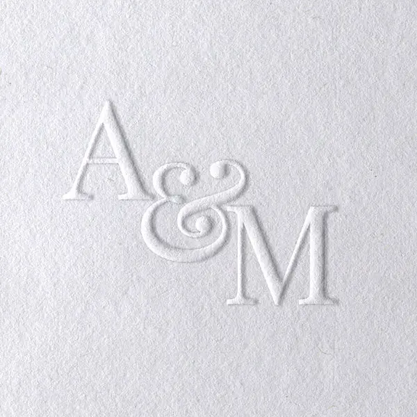 Biały papier z wypukłym tłoczeniem monogramu ślubnego liter połączonych ozdobnym znakiem AND