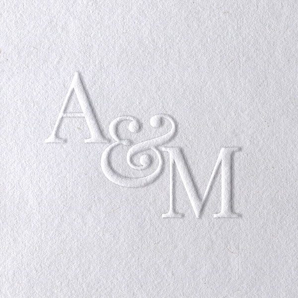 Biały papier z wypukłym tłoczeniem monogramu ślubnego liter połączonych ozdobnym znakiem AND